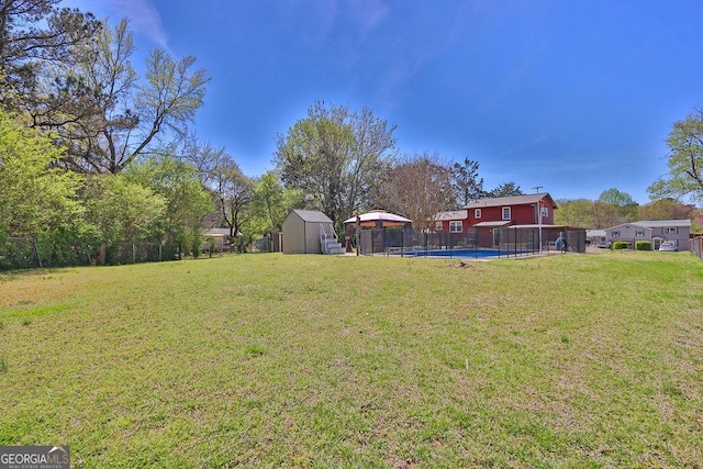 view of yard with a shed, an outbuilding, fence, and a fenced in pool