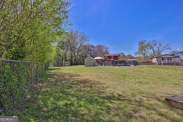 view of yard featuring a storage unit, a fenced backyard, and an outbuilding