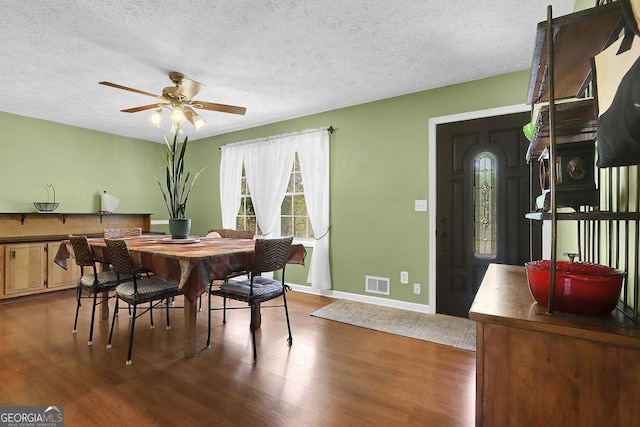 dining area with a textured ceiling, visible vents, wood finished floors, and a ceiling fan