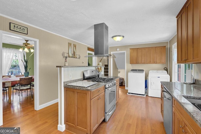 kitchen featuring independent washer and dryer, island range hood, light wood-type flooring, and appliances with stainless steel finishes
