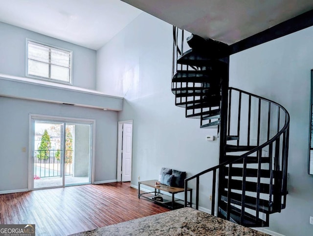 foyer entrance with stairs, a high ceiling, baseboards, and wood finished floors