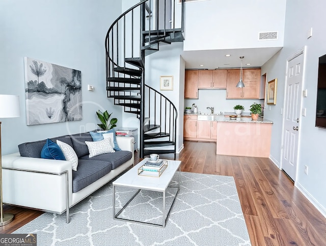 living area with visible vents, dark wood finished floors, a high ceiling, baseboards, and stairs