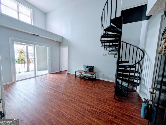 living area featuring stairway, baseboards, a high ceiling, and wood finished floors