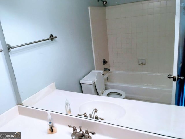 bathroom with tub / shower combination, toilet, and a sink