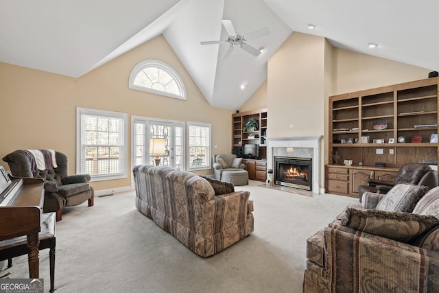 living room with high vaulted ceiling, light carpet, a ceiling fan, and a high end fireplace