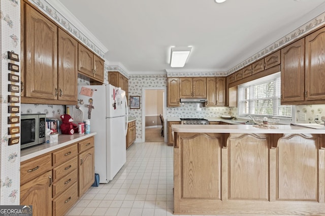 kitchen featuring stainless steel microwave, wallpapered walls, under cabinet range hood, a peninsula, and freestanding refrigerator