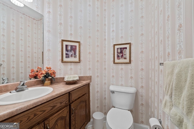 bathroom featuring wallpapered walls, toilet, and vanity