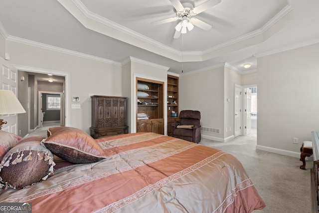 carpeted bedroom featuring visible vents, baseboards, crown molding, ensuite bathroom, and a raised ceiling