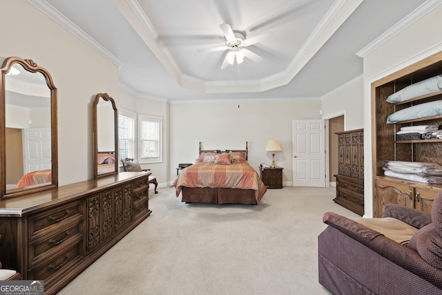 bedroom featuring a ceiling fan, a tray ceiling, crown molding, baseboards, and light colored carpet
