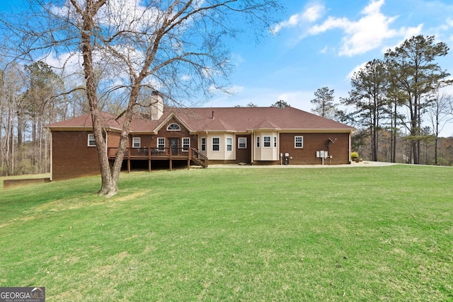 rear view of property featuring a lawn, a chimney, and a deck
