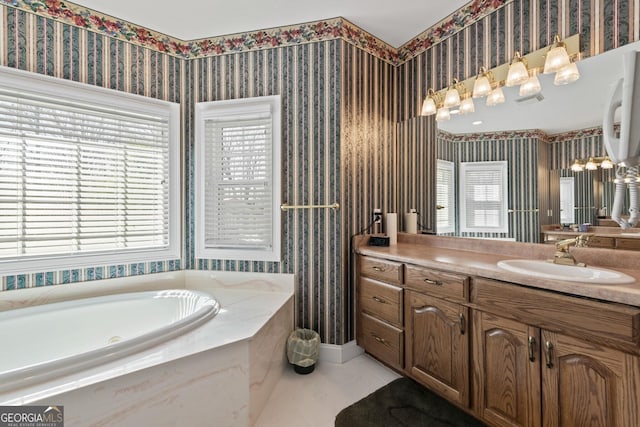 bathroom featuring a healthy amount of sunlight, a bath, vanity, and wallpapered walls