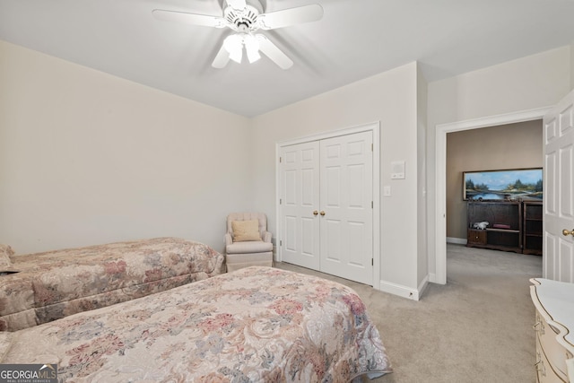 bedroom featuring a closet, light colored carpet, baseboards, and ceiling fan