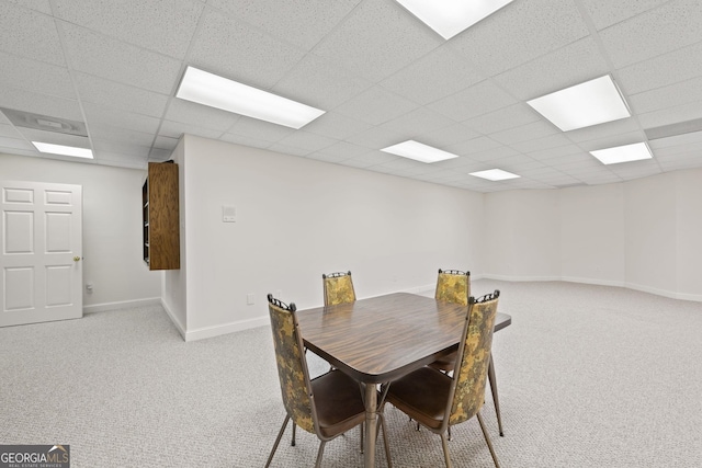 dining space with baseboards, a drop ceiling, and light carpet