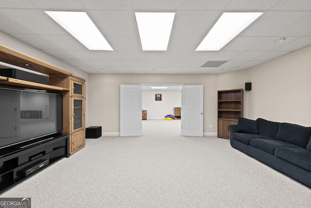carpeted living area with a drop ceiling and baseboards