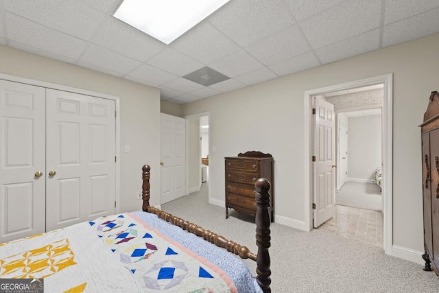 carpeted bedroom featuring baseboards, a closet, and a drop ceiling