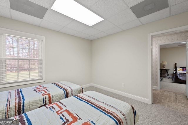 carpeted bedroom with a drop ceiling and baseboards