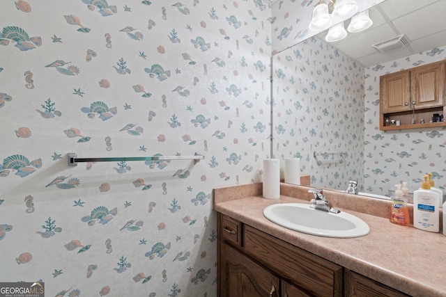 bathroom featuring visible vents, vanity, and wallpapered walls
