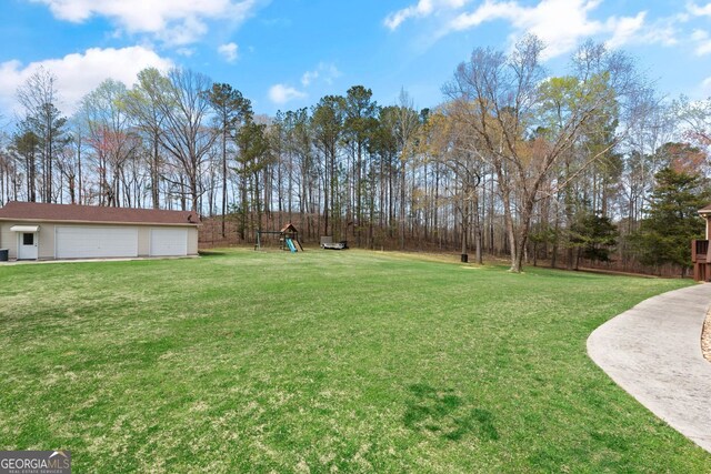 view of yard featuring a detached garage, an outbuilding, and a playground