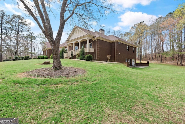 view of side of property featuring a yard, brick siding, and a chimney