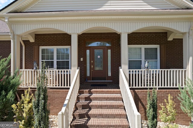 entrance to property featuring brick siding and covered porch