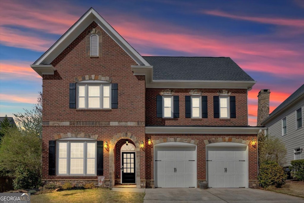 traditional-style home featuring a garage, brick siding, roof with shingles, and driveway
