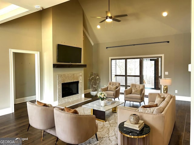living room featuring a high end fireplace, baseboards, ceiling fan, wood finished floors, and high vaulted ceiling