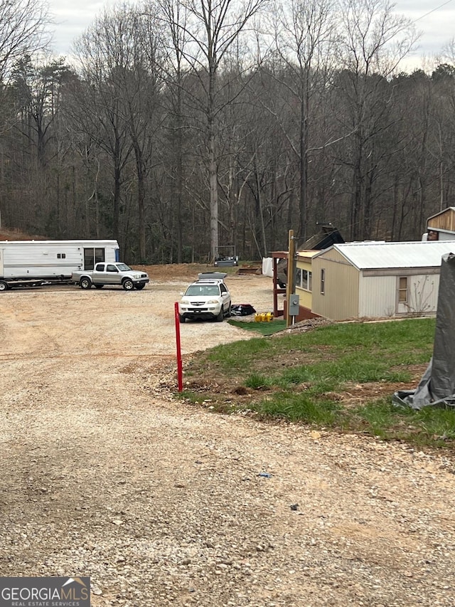 view of yard with a wooded view and driveway