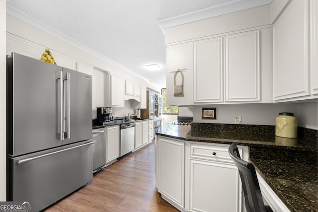 3530 Piedmont Rd NE Unit 3I, Atlanta, GA 30305 - kitchen featuring appliances with stainless steel finishes, white cabinets, wood finished floors, crown molding, and dark stone countertops