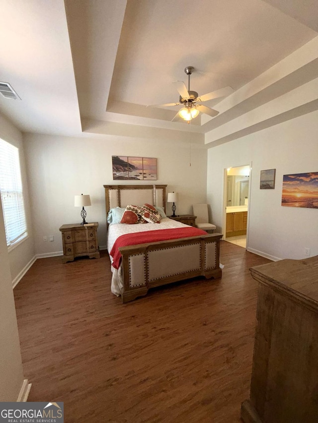 bedroom featuring a tray ceiling, visible vents, and wood finished floors