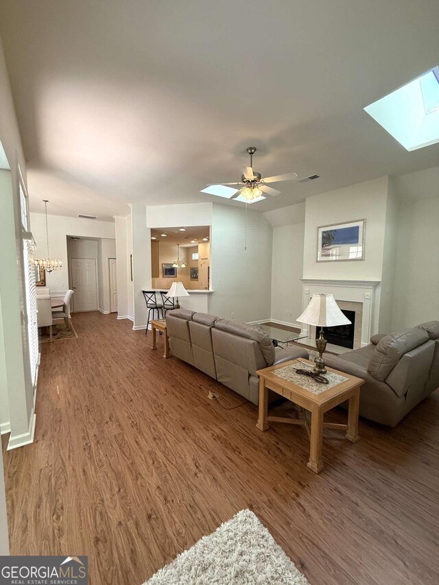 living area with visible vents, wood finished floors, a skylight, a fireplace, and baseboards