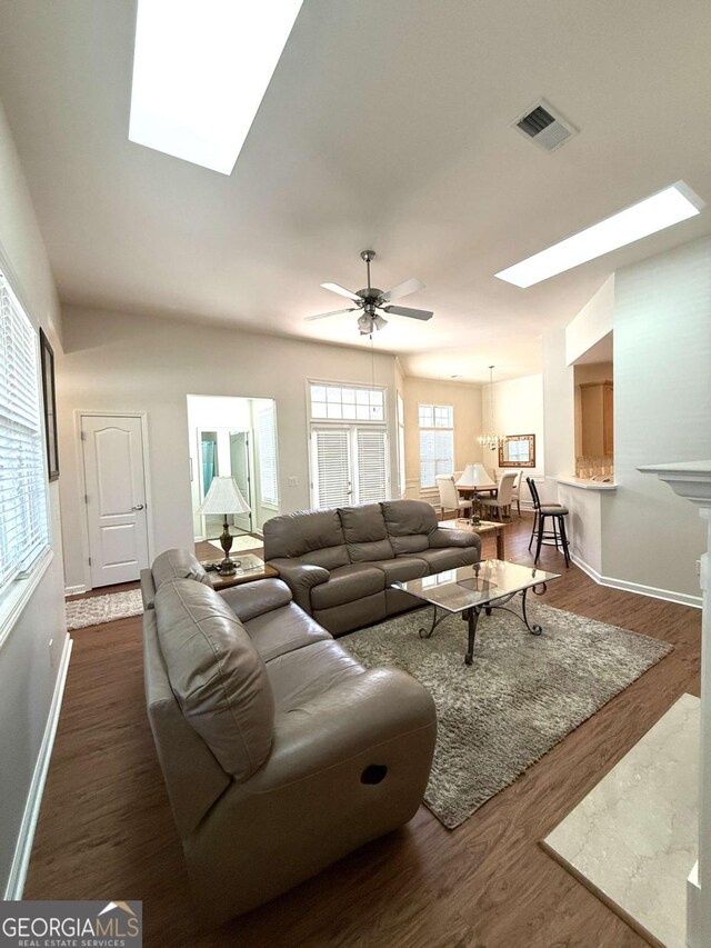 living area with ceiling fan, visible vents, dark wood-type flooring, and a skylight
