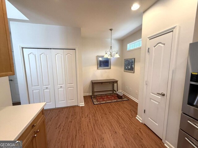 unfurnished dining area with a notable chandelier, wood finished floors, and baseboards