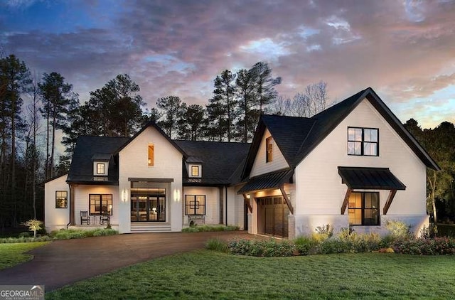 modern inspired farmhouse featuring a front lawn, an attached garage, and driveway