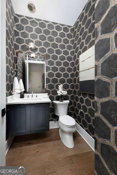 half bathroom with toilet, wood finished floors, and vanity