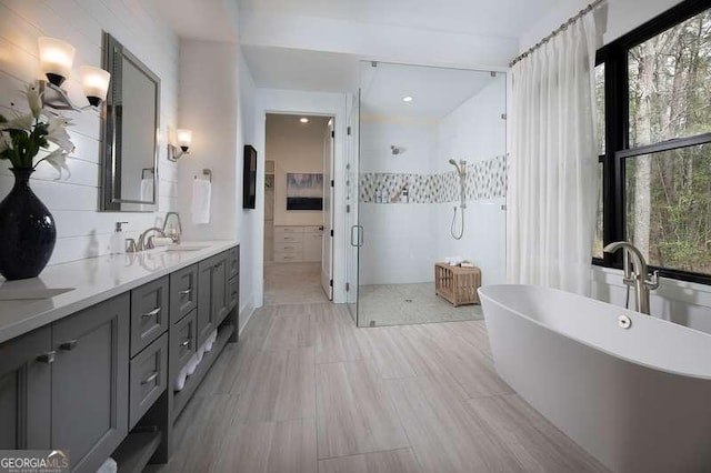 bathroom featuring a shower stall, a freestanding tub, double vanity, and a sink