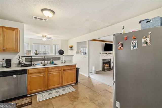 kitchen featuring visible vents, a sink, stainless steel appliances, a peninsula, and ceiling fan