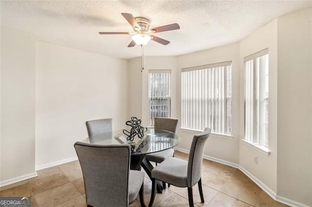 dining space featuring baseboards, a textured ceiling, and ceiling fan