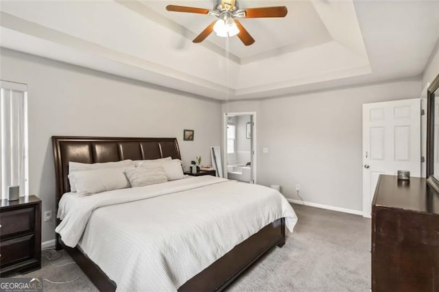 carpeted bedroom featuring baseboards, a raised ceiling, connected bathroom, and a ceiling fan