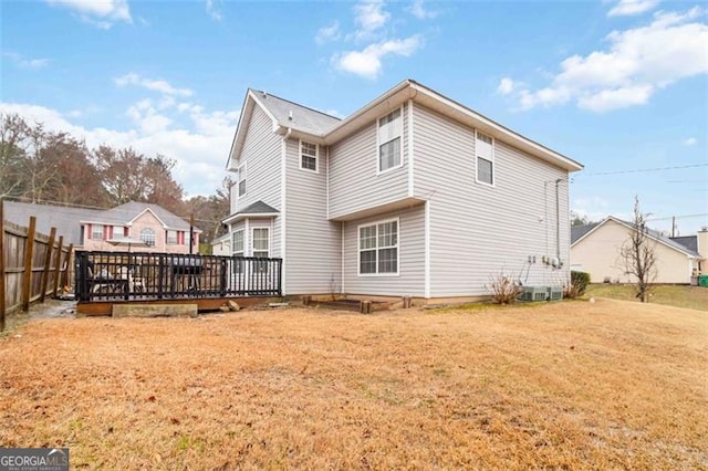 rear view of property featuring a deck, a lawn, and fence