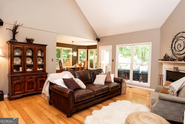 1041 Oconee Forest Ln, Watkinsville, GA 30677 - living room featuring light wood-style flooring, a chandelier, a fireplace, and high vaulted ceiling
