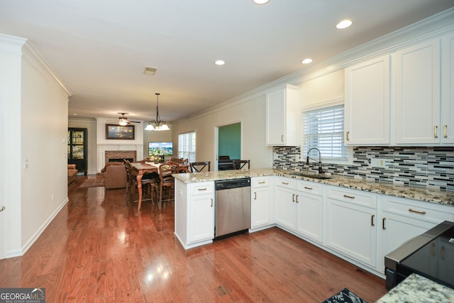 kitchen featuring stainless steel dishwasher, a peninsula, ornamental molding, and a sink