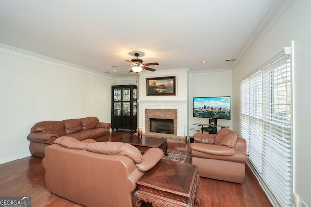 living area featuring plenty of natural light, a brick fireplace, wood finished floors, and crown molding