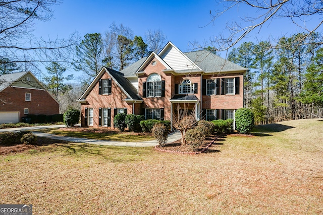 view of front of house featuring brick siding, roof with shingles, and a front yard