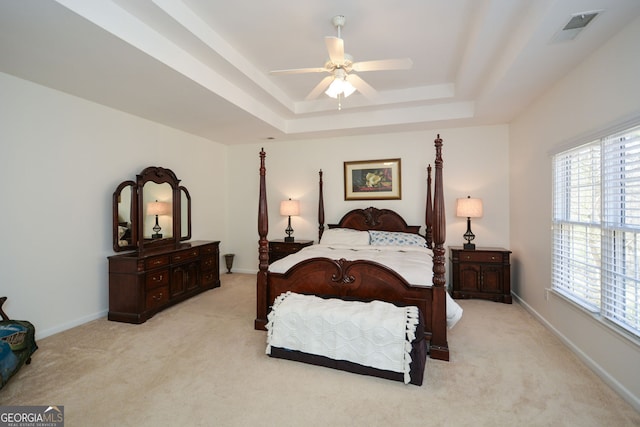 bedroom with visible vents, baseboards, ceiling fan, light colored carpet, and a raised ceiling