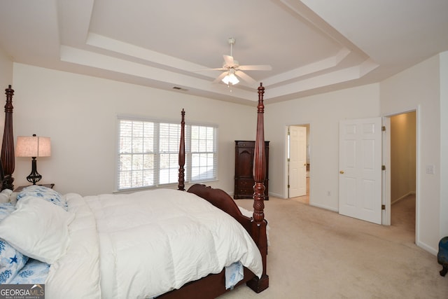 bedroom with a raised ceiling, baseboards, visible vents, and light carpet