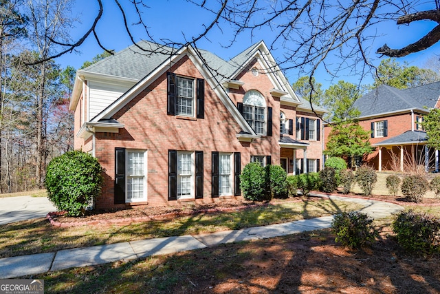 view of front of home featuring brick siding and a shingled roof