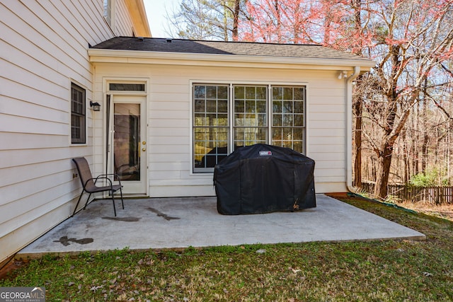 entrance to property featuring a patio area and roof with shingles
