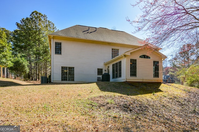 back of property with central air condition unit and a yard