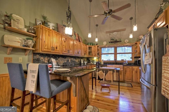 kitchen with light wood-type flooring, a breakfast bar, appliances with stainless steel finishes, a peninsula, and ceiling fan