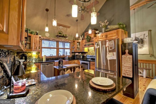 kitchen featuring brown cabinets, ceiling fan, glass insert cabinets, appliances with stainless steel finishes, and tasteful backsplash